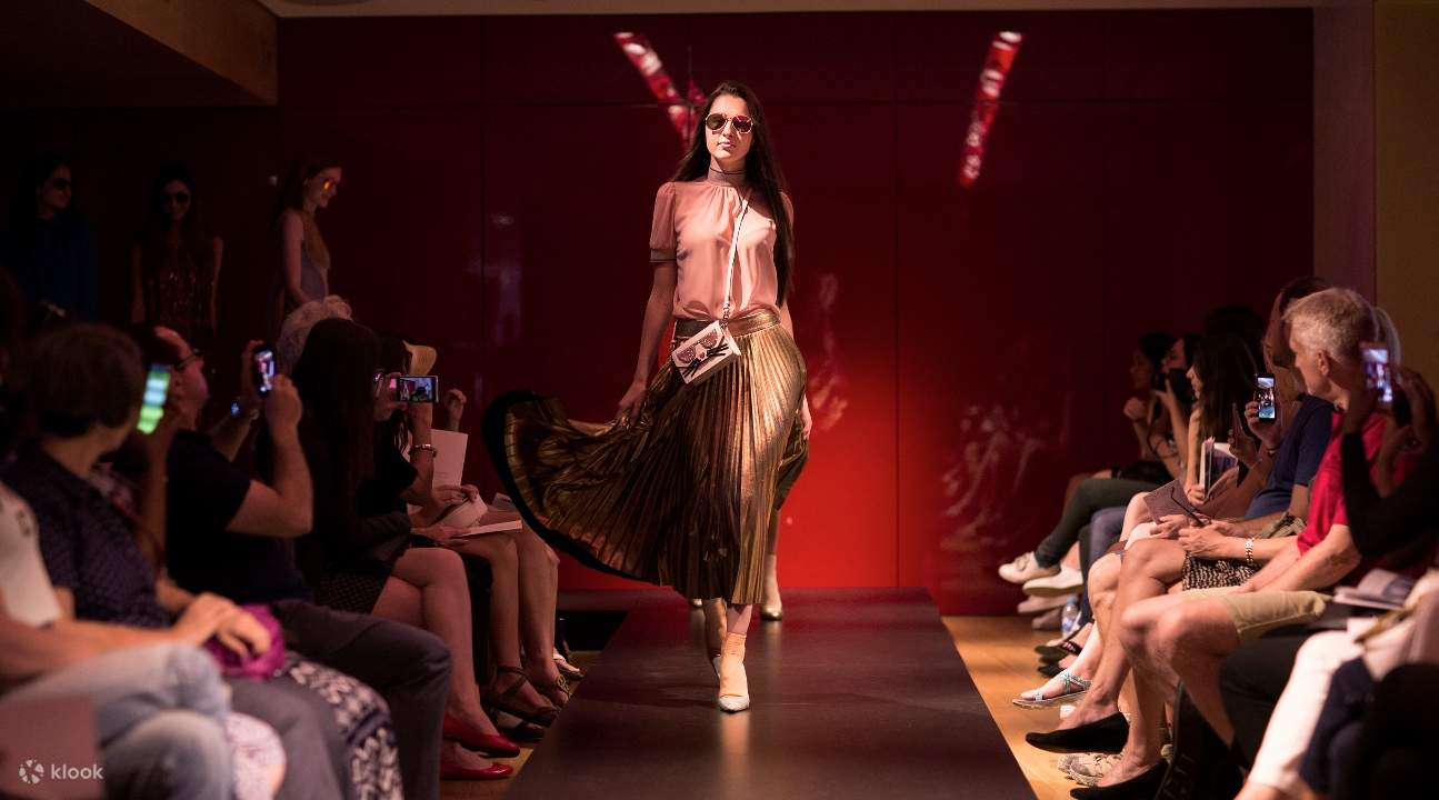 a fashion show; a woman in pink is strutting and showcasing a new item